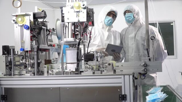 Group of engineer worker wearing ppe suite, face protective mask, glove useing digital tablet analyze  operation and check quality, Maintenance of mask manufacturing machine at lab in industry factory