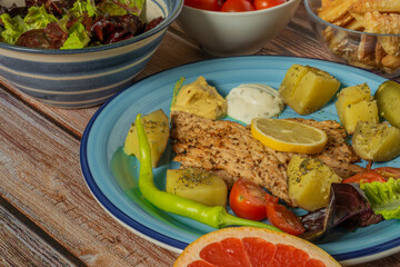 Vegetable fruit yoghurt apricot courgette chicken on blue plate and wooden table