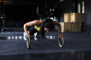 Fototapeta na wymiar Sporty indian strong woman doing push-ups on rings.