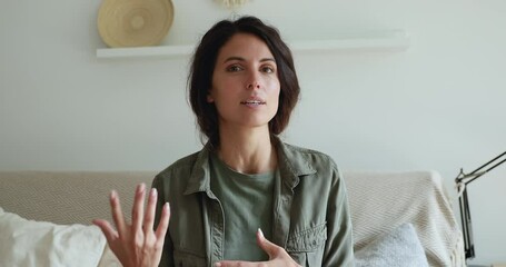 Head shot portrait woman sit on couch looks at web camera record new videoblog, makes a motivational speech, wave hand farewelling. Modern technology, promotional convincing video, influencing concept - Powered by Adobe