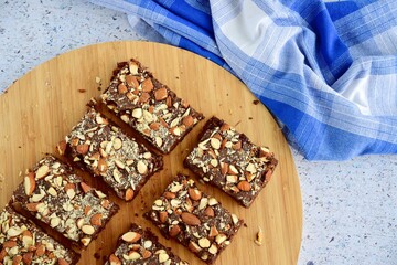 Fudge brownies dark chocolate cake topping with almond nuts on wooden board