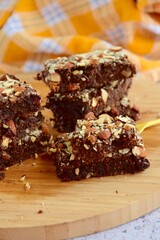 Fudge brownies dark chocolate cake topping with almond nuts on wooden board