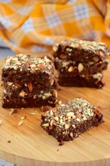 Fudge brownies dark chocolate cake topping with almond nuts on wooden board