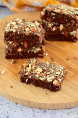 Fudge brownies dark chocolate cake topping with almond nuts on wooden board