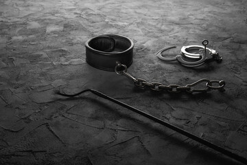 Auf dem Boden befestigtes Halsband mt Handschellen und Peitsche