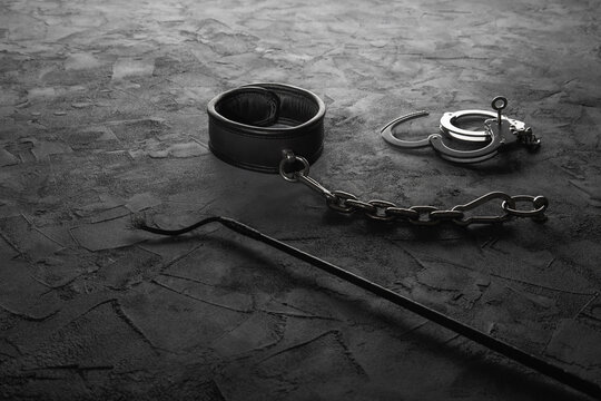 Auf dem Boden befestigtes Halsband mt Handschellen und Peitsche