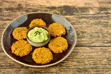 Homemade chickpea patties with guacamole dip and black sesame seeds
