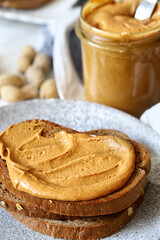 Peanut butter on toast with a jar in the background, healthy breakfast