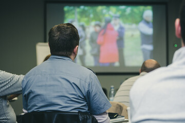 A man at a press conference looks at the projector screen