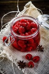 Sweet ripe raspberries in jar on wooden table