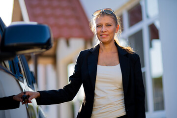 Beautiful woman real estate agent in suit and black car