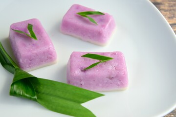Kue Talam Ubi Ungu, traditional Indonesian cake made from purple sweet potato, rice flour, tapioca flour and coconut milk. Garnish with pandan leaf served on white plate