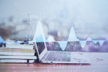 Stock market graph on background with desk and personal computer. Double exposure. Concept of financial analysis.