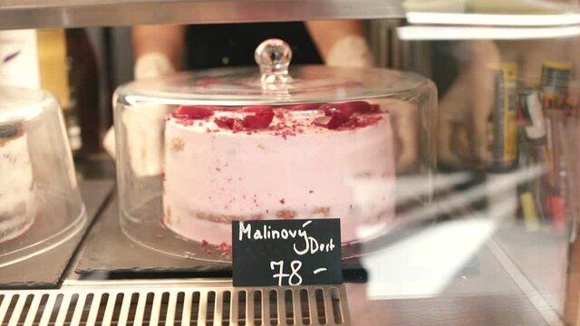 Confectionery showcase. Sale of desserts before the weekend. A raspberry cake in a Czech patisserie costs 78 CZK per piece. Transparent glass cover to keep food fresh. 