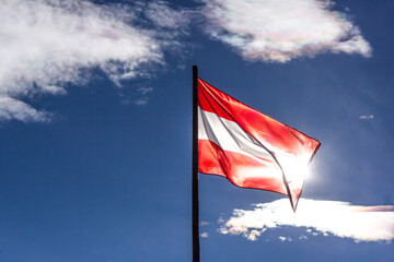 Waving flag of Austria backlit by the sun and with blue sky in the background