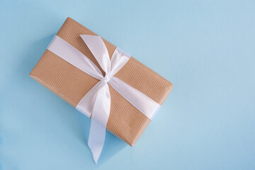 Gift in a craft package with a white ribbon on a blue background