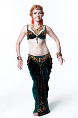 beautiful confident woman in green belly dance costume standing with hands near hips and looking at...