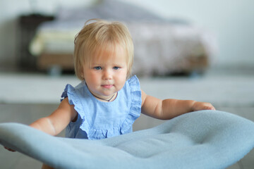 little blue-eyed girl learns to walk by holding on to the chair. happy baby face