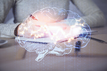 Double exposure of woman's writing hand on background with brain hud. Concept of learning.