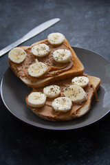 Peanut butter and banana toast isolated, dark background with copy space.
