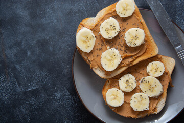 Peanut butter and banana toast isolated, dark background with copy space.