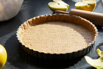 Raw shortbread dough for baking tart, apple pie and ingredients for home baking.