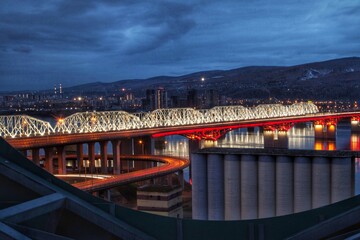 The bridge over the river glows beautifully with night lights.
