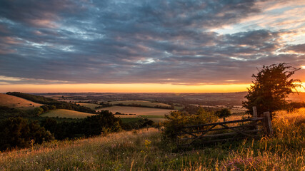 a wooden gate on a hill in the english countryside at sunset