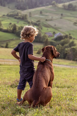 Curly boy and big dog sitting together - 386146359