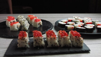 Set of Sushi Rolls with tuna, salmon, cucumber, avocado sprinkle with sesame seeds on black Background close-up. Assortment of Japanese food in restaurant.