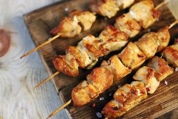 Selective focus. Appetizing chicken skewers on wooden sticks. Rustic style.