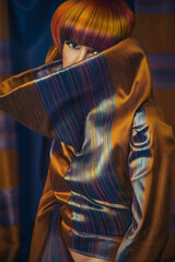 Fototapeta premium Portrait of a young woman wearing a copper and blue mock-neck outfit, posing with a colorful hairstyle while looking at the camera