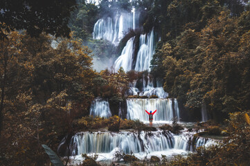 Man tourist on a rock in Thi Lo Su (Tee Lor Su) in Tak province. Thi Lo Su waterfall the largest waterfall in Thailand. This is a waterfall down a limestone hill originating of the mountain.