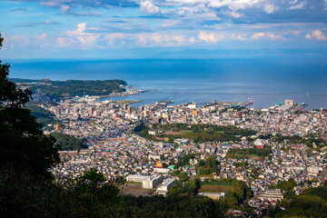 Fototapeta na wymiar 小樽山の展望台から見た、小樽の市街地とその奥にある石狩湾、雲の浮かぶ青空