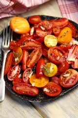 Selective focus. Rustic tomato salad with garlic and olive oil. Salad from different varieties of tomatoes.