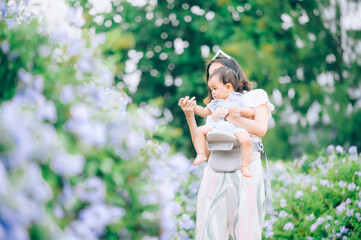 Obraz premium mother with little child in white blooming garden. woman with son in green leaves,happy family outdoors in spring