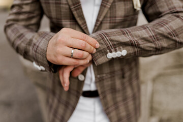 Naklejka premium Groom in brown plaid jacket looks at his ring on the finger. Advert for wedding agency