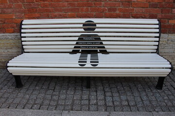 Park bench with an advertisement for social distance. 