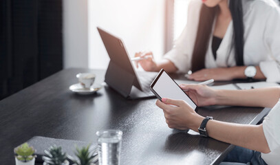 Cropped shot of two young female designer working with tablet together while sitting at office desk in modern office.
