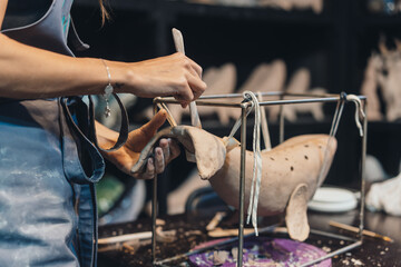 Close-up view of female hands gently handling a clay whale in workshop.