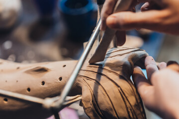Fototapeta na wymiar Close-up view of female hands gently handling a clay whale in workshop.
