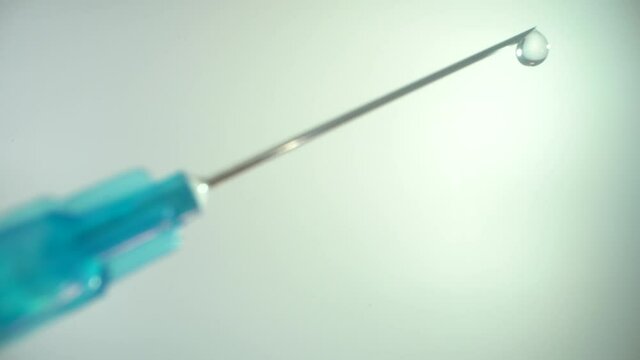 Syringe with a needle. at the end is a drop of preparation from a deadly virus. Covid-19 concept. Macro shot of medicine