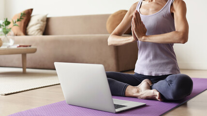 Young woman practicing yoga at home, online video training, Girl doing exercises and meditate,...
