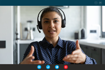 Head shot portrait screen view Indian businesswoman wearing headset speaking, looking at camera,...
