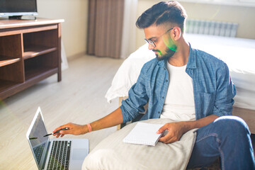 indian bearded male sitting on the floor and making making financial calculations online business in new apartment