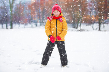 Child in winter. The boy plays on the street against the background of snow.