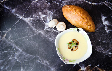 Fototapeta na wymiar Mushroom cream soup close-up. Champignon soup puree, pie and champignon on a dark granite background. Tasty winter vegetarian food.