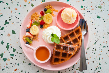Waffle with ice cream, whip cream, banana, strawberry, kiwi and honey.