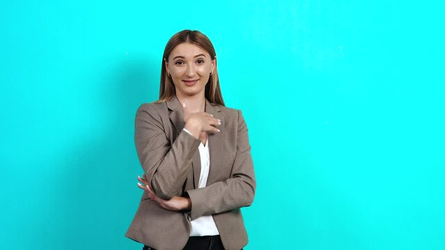 Wonderful cheerful woman, with sarcasm and derision, pointing to the room and smiling, making fun of people, selfishness. Studio image indoors, isolated on blue background