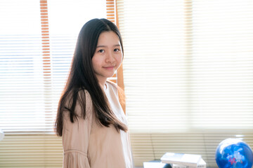 Beautiful teenager asian woman standing near window curtain